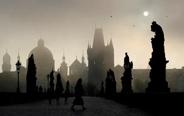 People walk across the medieval Charles Bridge as the sun rises in Prague, Czech Republic, October 1, 2020. (Photo by David W. Cerny/Reuters)