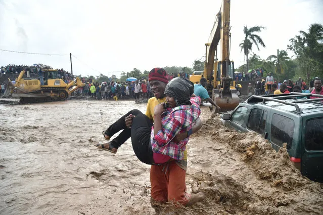 A woman is carried across the river La Digue in Petit Goave where the bridge collapsed during the rains of the Hurricane Matthew, southwest of Port-au-Prince, October 5, 2016. (Photo by Hector Retamal/AFP Photo)