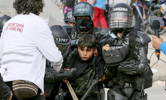 Riot police arrest a demonstrator during a protest demanding an increase in public transport and services proposed by members of the government, in Usme neighborhood, south Bogota on January 6, 2022. (Photo by Leonardo Munoz/AFP Photo)