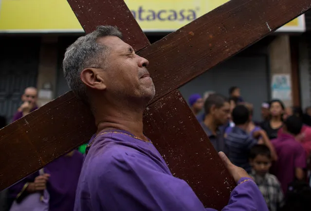 A man carries a cross during the procession of the “Nazareno de San Pablo” outside Santa Teresa Cathedral during Holy Week in Caracas, Venezuela, Wednesday, March 28, 2018. (Photo by Ariana Cubillos/AP Photo)