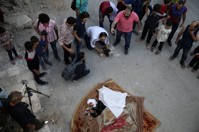 Syrian director Humam Husari (wearing pink) directs actors while cameraman Sami al-Shami operates a camera as they film a scene in the rebel-held besieged town of Zamalka, in the Damascus suburbs, Syria September 19, 2016. (Photo by Bassam Khabieh/Reuters)