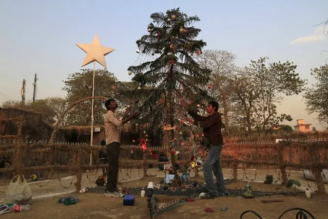 Men decorate a Christmas tree ahead of Christmas in a Christian slum in Islamabad December 23, 2014. (Photo by Faisal Mahmood/Reuters)