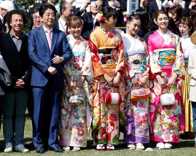 Japan's Prime Minister Shinzo Abe poses with members of pop group E-girls in kimonos during a cherry blossom viewing party at Shinjuku Gyoen park in Tokyo, Japan, April 21, 2018. (Photo by Toru Hanai/Reuters)