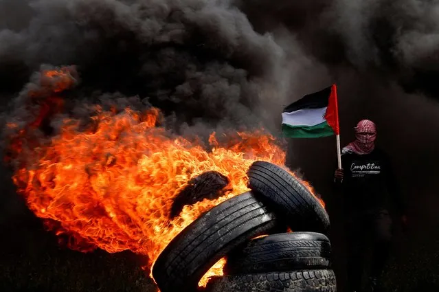 A man holds a Palestinian flag during a protest against Israeli-Palestinian meeting in Sharm el-Sheikh, at the Israel-Gaza border fence east of Gaza City on March 19, 2023. (Photo by Mohammed Salem/Reuters)