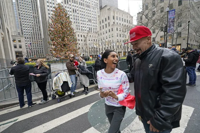 Family members laugh as they walk past by the Rockefeller Center Christmas tree, where fewer than normal people were gathered, Thursday, December 24, 2020, on Christmas Eve in New York. (Photo by Kathy Willens/AP Photo)