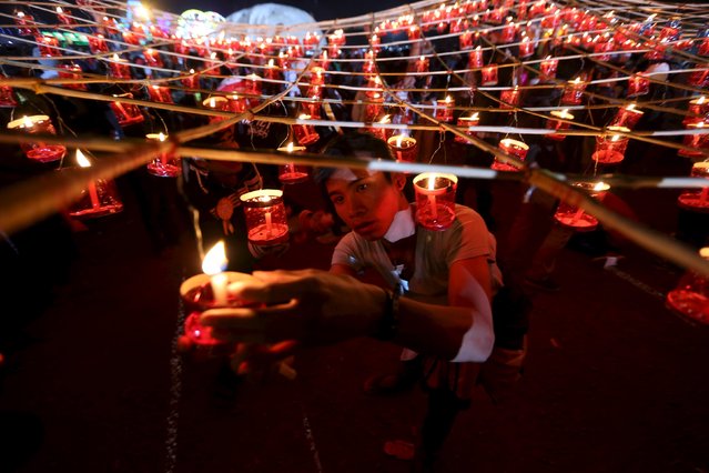 People light candles before releasing a traditional home-made paper balloon into the sky during the annual Tazaungdaing festival in Taunggyi, Myanmar November 19, 2015. (Photo by Soe Zeya Tun/Reuters)