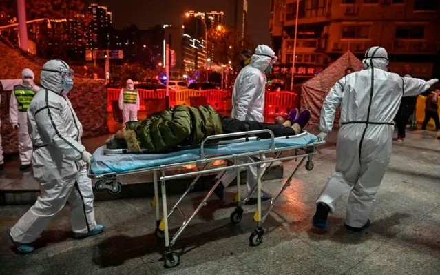 Medical staff members wearing protective clothing to help stop the spread of a deadly virus which began in the city, arrive with a patient at the Wuhan Red Cross Hospital in Wuhan on January 25, 2020. The Chinese army deployed medical specialists on January 25 to the epicentre of a spiralling viral outbreak that has killed 41 people and spread around the world, as millions spent their normally festive Lunar New Year holiday under lockdown. (Photo by Hector Retamal/AFP Photo) 