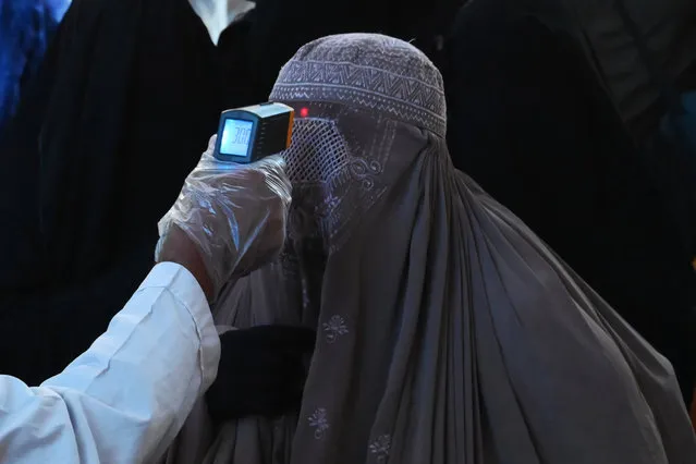 A health official checks the body temperature of a burqa-clad woman passenger amid concerns over the spread of the COVID-19 novel coronavirus at the Lahore Railway station in Lahore on March 19, 2020. (Photo by Arif Ali/AFP Photo)