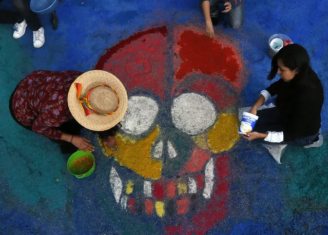 Residents create a sawdust representation of a skull during Day of the Dead festivities in Mexico City, Thursday, October 27, 2016. (Photo by Marco Ugarte/AP Photo)