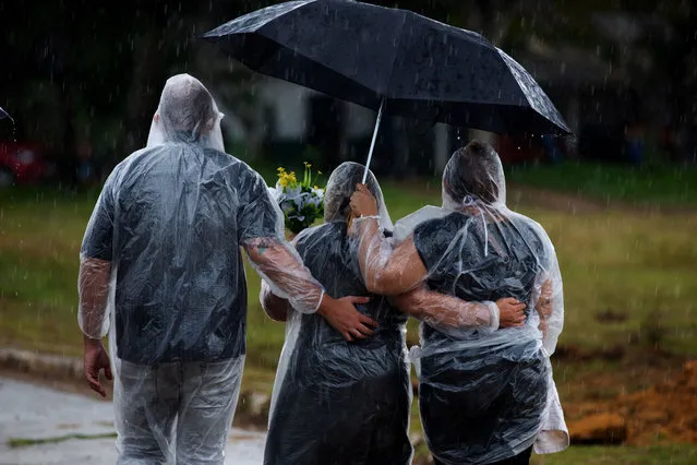 Relatives attend a COVID-19 victim’s burial under the rain, at the Nossa Senhora Aparecida cemetery in Manaus, Amazonas state, Brazil, on January 13, 2021, amid the novel coronavirus pandemic. In Manaus there is a shortage of hospital beds as cases increased at an alarming rate. The city, with two million inhabitants, had already experienced nightmarish scenes in April and May, with mass graves and refrigerated trucks parked in front of hospitals to pile up the dead. But the situation is even worse in the beginning of 2021, since between January 1 and 11, at least 1,979 people were admitted to hospitals due to the virus, against 2,128 for the whole month of April, the worst since the start of the pandemic. (Photo by Michael Dantas/AFP Photo)