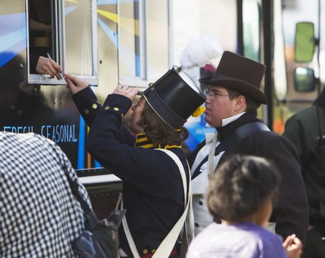 Men dressed in period costumes order from a food truck during a commemoration of the Battle of New Orleans in the War of 1812, marking its bicentennial in Chalmette, Louisiana January 10, 2015. (Photo by Lee Celano/Reuters)