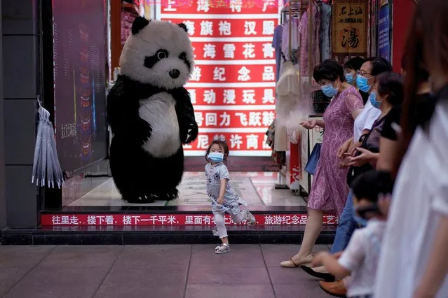 A little girl wearing a face mask dances in front of a toy panda at a shopping area in Shanghai, following the coronavirus disease (COVID-19) outbreak, China on June 16, 2020. (Photo by Aly Song/Reuters)