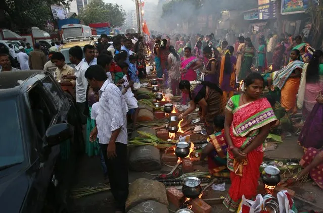 Indian Tamil Hindu women cook special food to celebrate the harvest festival of Pongal on a road at Dharavi, one of the world’s largest slums, in Mumbai, India, Thursday, January 15, 2015. This celebration, held according to the solar calendar, marks the beginning of the sun's northward movement, considered to be auspicious. (Photo by Rafiq Maqbool/AP Photo)