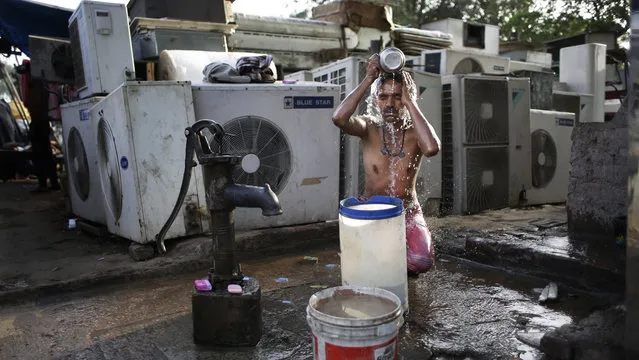 An Indian migrant daily wage worker baths at a public well pump on a hot morning in New Delhi, India, Tuesday, May 17, 2016. Scorching summer temperatures, hovering well over 40 degrees Celcius, (104 Fahrenheit) are making life extremely tough for millions of poor across north India. Without access to air conditioning and sometimes even an electric fan, they struggle to cope with the heat in their inadequate homes. (Photo by Altaf Qadri/AP Photo)