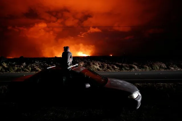 In this May 19, 2018 file photo, Brittany Kimball watches as lava erupts from a fissure near Pahoa, Hawaii. White plumes of acid and extremely fine shards of glass billowed into the sky over Hawaii as molten rock from Kilauea volcano poured into the ocean, creating yet another hazard from an eruption that began more than two weeks ago: A toxic steam cloud. (Photo by Jae C. Hong/AP Photo)