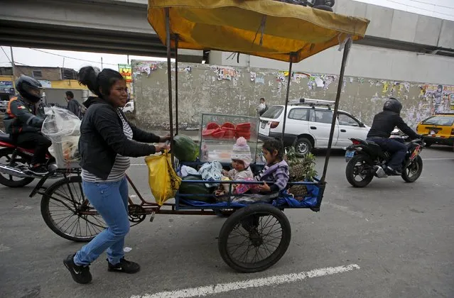 A woman sells fruits while children sit in a tricycle cart in downtown Lima, Peru December 1, 2015. (Photo by Mariana Bazo/Reuters)