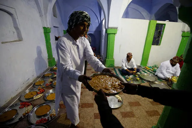 A Muslim man prepares plates of food for Iftar (breaking fast) meals inside a mosque during the holy month of Ramadan in Ahmedabad, India, June 13, 2018. (Photo by Amit Dave/Reuters)