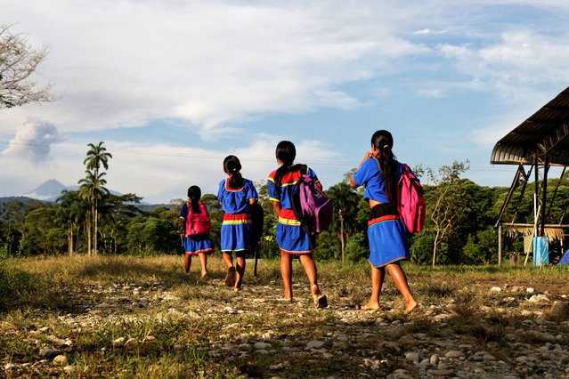 Girls from the A’i Cofan indigenous community walk to school against the backdrop of the Reventador volcano during a meeting of indigenous guards from communities across the region, who aim to defend the natural resources of the Amazon from exploitation, in Sinangoe, Ecuador, on December 3, 2025. (Photo by Karen Toro/Reuters)