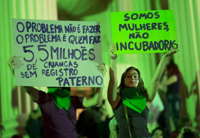 A demonstrator, right, holds a sign with a message that reads in Portuguese: “We are women, not incubators”, as she joins others in a protest demanding the legalization of abortion without exception, in Rio de Janeiro, Brazil, Friday, June 22, 2018. Abortion is illegal in Brazil, except when a woman's life is at risk, when she has been raped or when the fetus has a usually fatal brain abnormality called anencephaly. (Photo by Silvia Izquierdo/AP Photo)