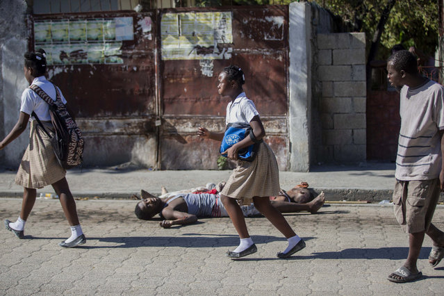Students rush past the bodies of inmates outside the Croix-des-Bouquets Civil Prison after an attempted breakout, in Port-au-Prince, Haiti, Thursday, February 25, 2021. At least seven people were killed and one injured on Thursday after eyewitnesses told The Associated Press that several inmates tried to escape from a prison in Haiti’s capital. (Photo by Dieu Nalio Chery/AP Photo)