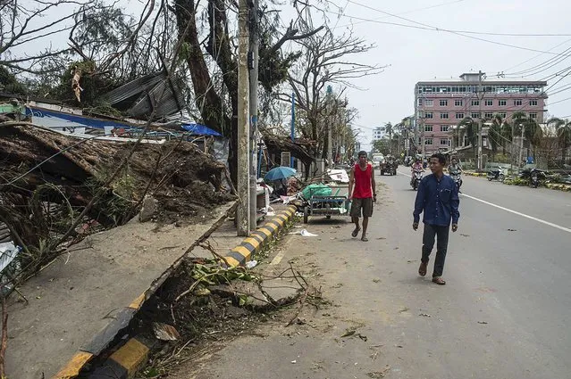Local people walk past damaged buildings after Cyclone Mocha in Sittwe township, Rakhine State, Myanmar, Monday, May 15, 2023. (Photo by AP Photo/Stringer)