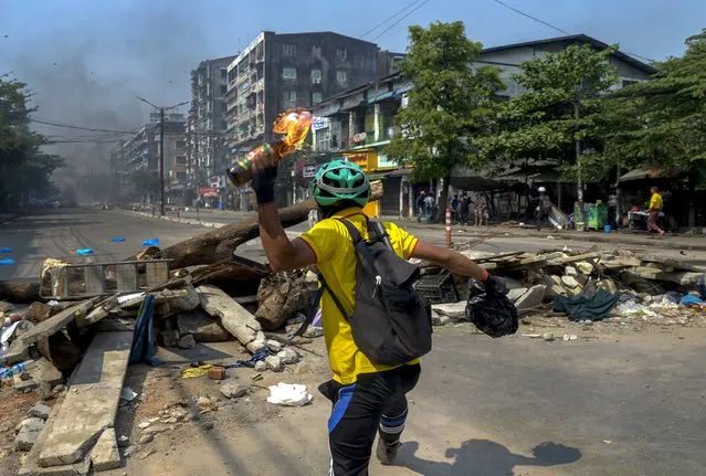An anti-coup protester throws a molotov cocktail towards police as they move towards the protest area in Yangon, Myanmar Wednesday, March 17, 2021. (Photo by AP Photo/Stringer)