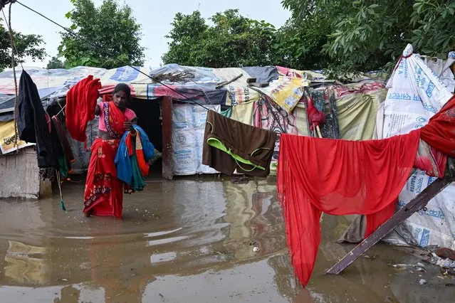 A woman collects her belongings before relocating from a low lying area near the Yamuna River after it overflowed due to monsoon rains, in New Delhi on July 11, 2023. (Photo by Arun Sankar/AFP Photo)
