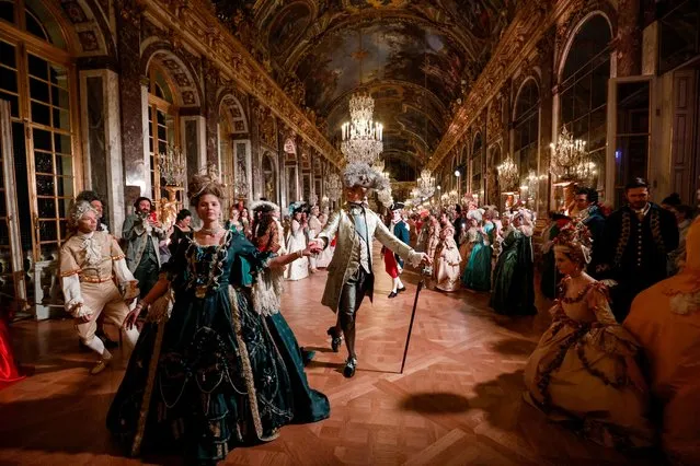 Guests wearing baroque style costumes walk in the Hall of Mirrors at the Chateau de Versailles Palace as part of the sixth edition's of the Fetes Galantes fancy dress evening which theme is the Royal Wedding of Marie Antoinette and Louis XVI, in Versailles on May 23, 2022. The annual fancy dress ball aims to re-create the baroque splendour of the Sun King's dazzling court feasts held to show off the wealth and power of France's longest-reigning monarch. For tickets costing more than five hundred euros, guests can wander through the private apartments of the chateau, which is a World Heritage site and one of France's biggest tourist attractions. (Photo by Ludovic Marin/AFP Photo)
