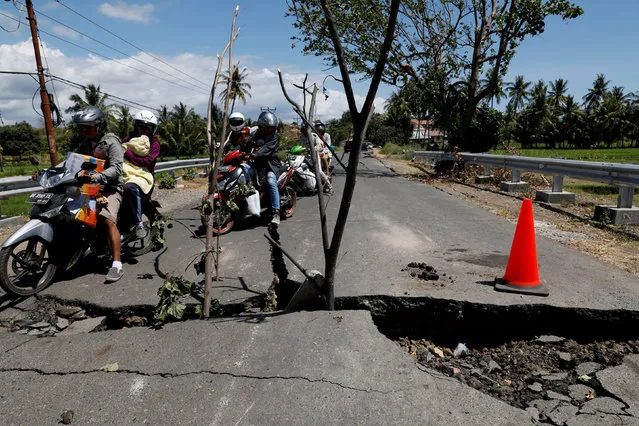 A family rides on a motorcycle through a crack on the street at Kayangan district after earthquake hit on Sunday in North Lombok, Indonesia, August 7, 2018. (Photo by Reuters/Beawiharta)