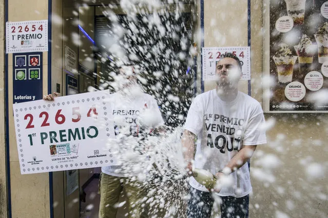 A man uncorks a bottle of sparkling wine as he celebrates the first prize of 'El Nino' lottery draw in Malaga, southern Spain, 06 January 2016. The first prize of 200,000 euros went to lottery ticket number 22,654. Spain holds its traditional lottery draw 'El Nino' on Epiphany Day and, although its prizes are less substantial than the famous Christmas draw 'El Gordo', Spaniards celebrate this draw as part of the traditional Christmas joy. (Photo by Jorge Zapata/EPA)