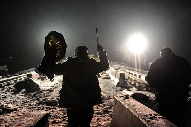 A man holds up a traditional drum during a confrontation between veterans and police on Backwater bridge during a protest against plans to pass the Dakota Access pipeline near the Standing Rock Indian Reservation, near Cannon Ball, North Dakota, U.S., December 1, 2016. (Photo by Stephanie Keith/Reuters)