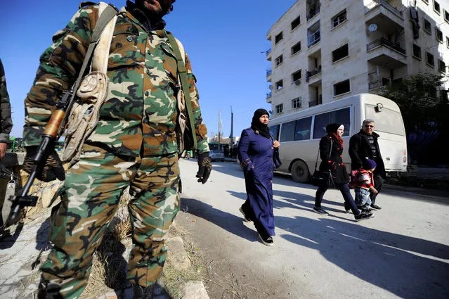 People that came back to inspect their homes walk near goverment soldiers in goverment controlled Hanono housing district in Aleppo, Syria December 4, 2016. (Photo by Omar Sanadiki/Reuters)