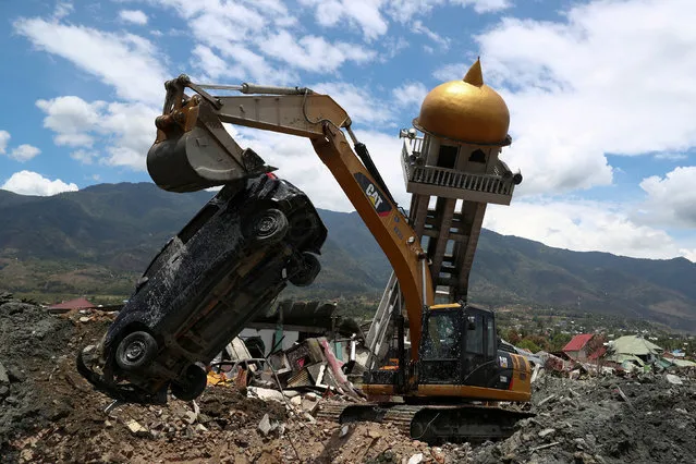 An excavator removes a damaged car next to the debris of a mosque damaged by an earthquake in the Balaroa neighbourhood in Palu, Central Sulawesi, Indonesia, October 8, 2018. (Photo by Athit Perawongmetha/Reuters)
