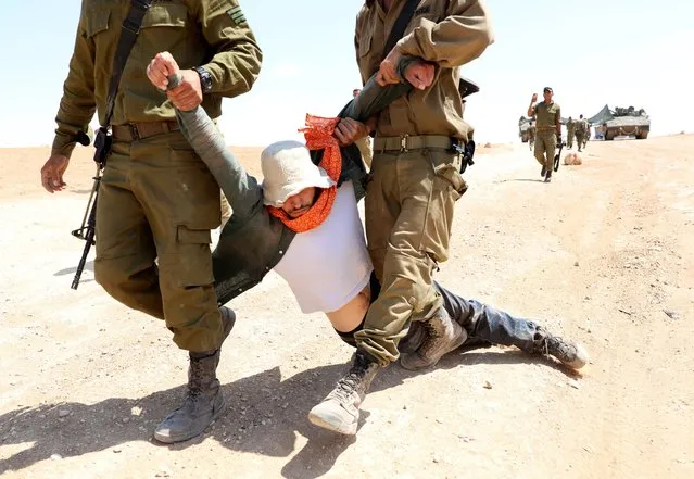 Israeli soldiers detain activists during a protest against an Israeli military drill and possible eviction of Palestinians in the West Bank village of Yatta, 22 June 2022. According to Palestinian activists group, Israeli forces on 22 June detained a group of international solidarity activists in Masafer Yatta, South of Hebron, during a protest against Israeli military drills. Israel's supreme court rejected on 07 May a petition against the evictions from Masafer Yatta, that could result in the expelling of some 1,300 Palestinians living in villages in the area. (Photo by Abed Al Hashlamoun/EPA/EFE)