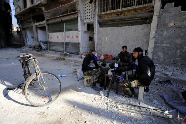 Forces loyal to Syria's President Bashar al-Assad sit in front of damaged shops in a government held area of Aleppo, Syria December 9, 2016. (Photo by Omar Sanadiki/Reuters)