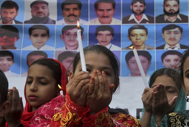 Pakistani children hold candles and pray for victims of an attack on a Peshawar school in 2014, during a ceremony to mark second anniversary of the attack, in Peshawar, Pakistan, Friday, December 16, 2016. Pakistani Taliban militants attacked an army-run school in Peshawar, killing more than 150 people, mostly children, on Dec. 16. 2014. (Photo by Muhammad Sajjad/AP Photo)