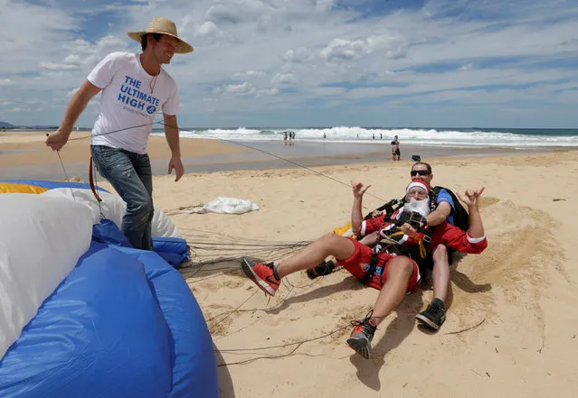 Tandem skydivers Sebastian Terry (in Santa suit) and Luke Biggs land on a beach after being guided in by Skydive Australia CEO Anthony Boucaut (L) as 155 skydives sets the new Guinness World Record number of tandem skydivers over eight hours in the Australian city of Wollongong, December 17, 2016. (Photo by Jason Reed/Reuters)