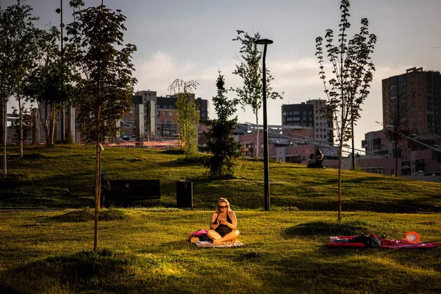 A picture taken on June 21, 2021 shows a woman using her mobile phone as she enjoys a hot summer evening in a park in Moscow, where temperatures have reached 30 degrees Celsius. (Photo by Dimitar Dilkoff/AFP Photo)