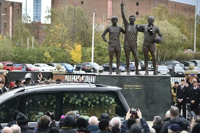 The cortege of English soccer icon Bobby Charlton passes by the statue of Manchester United trio of George Best, left, Denis Law, center, and Sir Bobby Charlton outside Old Trafford stadium on its way to the funeral service at Manchester Cathedral in Manchester, England, Monday, November 13, 2023. Charlton who played largely for Manchester United survived a plane crash that decimated a United team destined for greatness, he went on to became the heartbeat of his country's 1966 World Cup triumph. (Photo by Rui Vieira/AP Photo)
