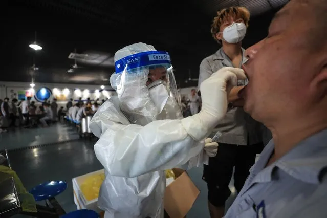 A worker receives a nucleic acid test for the Covid-19 coronavirus at the dining hall of a car parts factory in Wuhan, in China's central Hubei province on August 4, 2021. (Photo by AFP Photo/China Stringer Network)