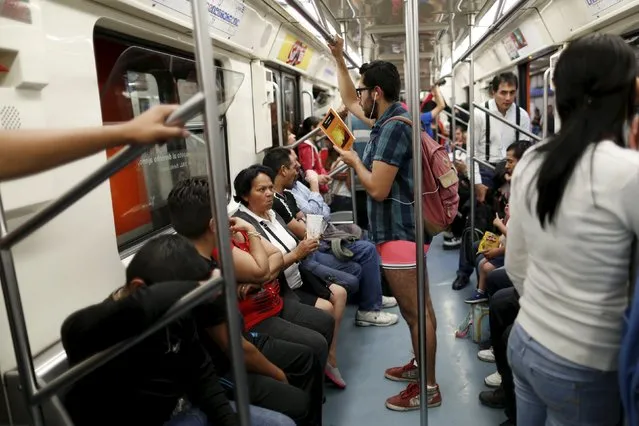 A passenger not wearing pants stands as he reads a book inside a subway train during the “No Pants Subway Ride” in Mexico City, Mexico, February 21, 2016. (Photo by Carlos Jasso/Reuters)