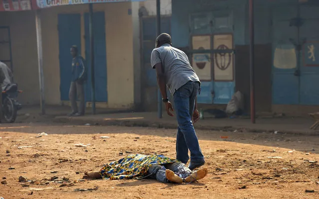 A man from the Muslim community looks at a corpse lying on a road in the PK5 district of Bangui on January 3, 2014. France's military mission in the Central African Republic will not suck in its troops in an expanding role, Defence Minister Jean-Yves Le Drian vowed during a visit to the restive country's capital. (Photo by Miguel Medina/AFP Photo)