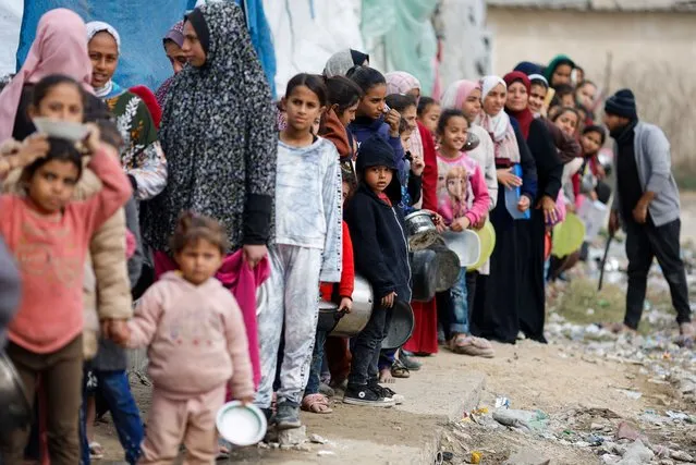Palestinians stand in a line as they wait to receive food in Rafah in the southern Gaza Strip on January 17, 2024. (Photo by Mohammed Salem/Reuters)