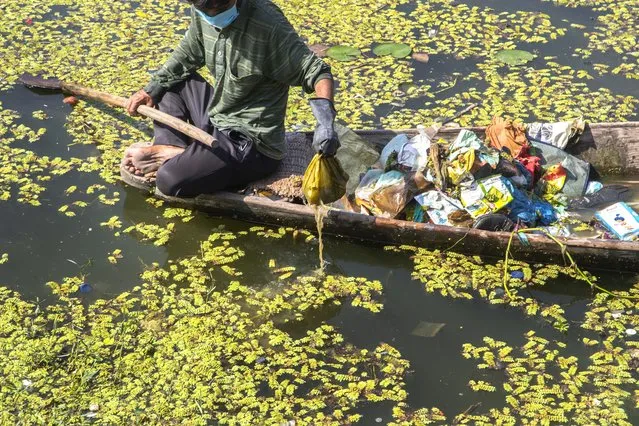 A Kashmiri boatman employed by the Lakes and Waterways Development Authority removes garbage from the Dal Lake in Srinagar, Indian controlled Kashmir, Tuesday, September 14, 2021. (Photo by Mukhtar Khan/AP Photo)
