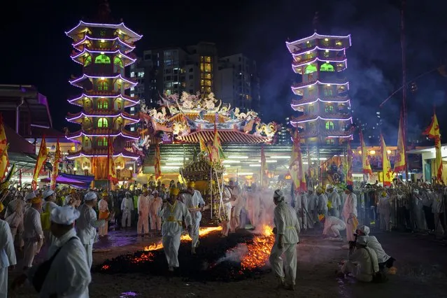 Malaysian Chinese carrying an Emperor God walk barefoot over burning coals on the final day of the Nine Emperor Gods festival at a temple in Kuala Lumpur, Malaysia, Monday, October 23, 2023. The men have abstained from meat for the past nine days in order to purify their bodies in preparation for this ritual, in which women are barred from participating. (Photo by Vincent Thian/AP Photo)