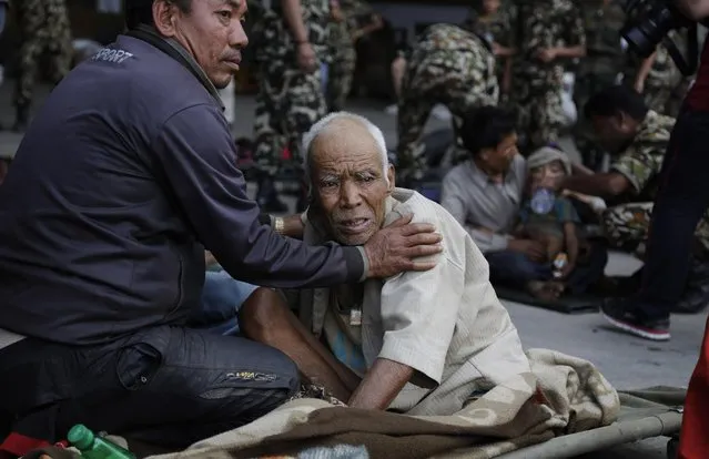 A Nepalese man attends to an elderly as victims of Saturday's earthquake, wait for ambulances after being evacuated at the airport in Kathmandu, Nepal, Monday, April 27, 2015. (Photo by Altaf Qadri/AP Photo)
