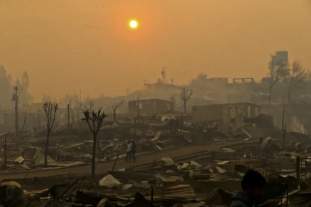 In this Thursday, January 26, 2017 photo, a couple walks through a neighborhood destroyed by wildfires in Chile's Santa Olga community. Officials say the town was consumed by the country's worst wildfires, engulfing the post office, a kindergarten and hundreds of homes. (Photo by Esteban Felix/AP Photo)