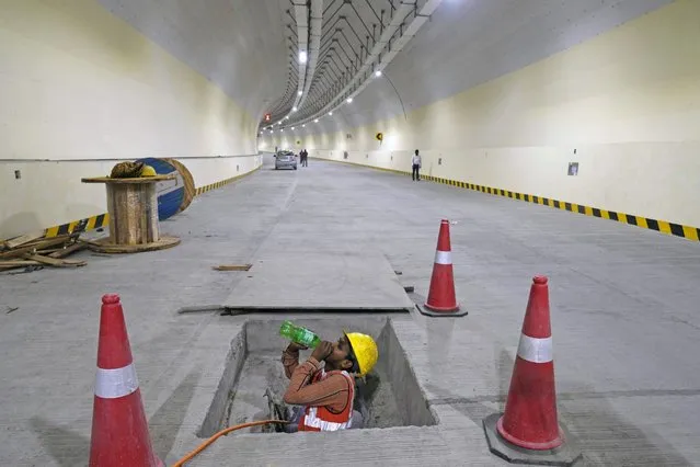 A construction worker takes a break inside a tunnel at the site of a coastal road building project in Mumbai, India, Thursday, January 25, 2024. (Photo by Rajanish Kakade/AP Photo)