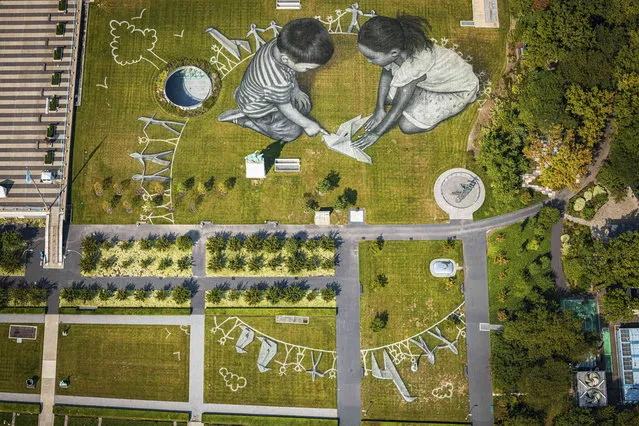 An aerial view shows the giant ephemeral landart painting entitled “World in Progress II” by Swiss-French artist Saype (Guillaume Legros) representing two children drawing and building with origami their ideal world, at the Headquarters of the United Nations (U.N.) in New York City, USA, Wednesday, September 15, 2021. The artwork covering 11'000 square meters (118'000 sq ft) was produced with biodegradable paints made from natural pigments such as charcoal and chalk and constitutes the second step of a project started at the U.N. European headquarters in Geneva in 2020. The project is supported and gifted by Switzerland to the U.N. to celebrate the 75th anniversary of the organization and the launch of the Common Agenda. (Photo by Valentin Flauraud/Keystone via AP Photo)
