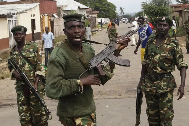 Soldiers disperse a crowd by firing into the air after demonstrators cornered Jean Claude Niyonzima a suspected member of the ruling party's Imbonerakure youth militia in a sewer in the Cibitoke district of Bujumbura, Burundi, Thursday May 7, 2015. (Photo by Jerome Delay/AP Photo)